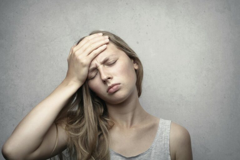 stressed out woman holding her forehead in gray tank top